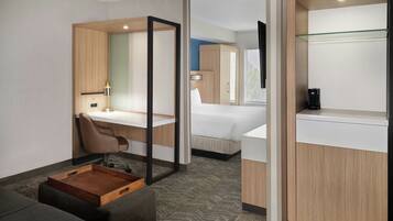 A modern hotel room with a desk, chair, bed, and a small wooden side table.