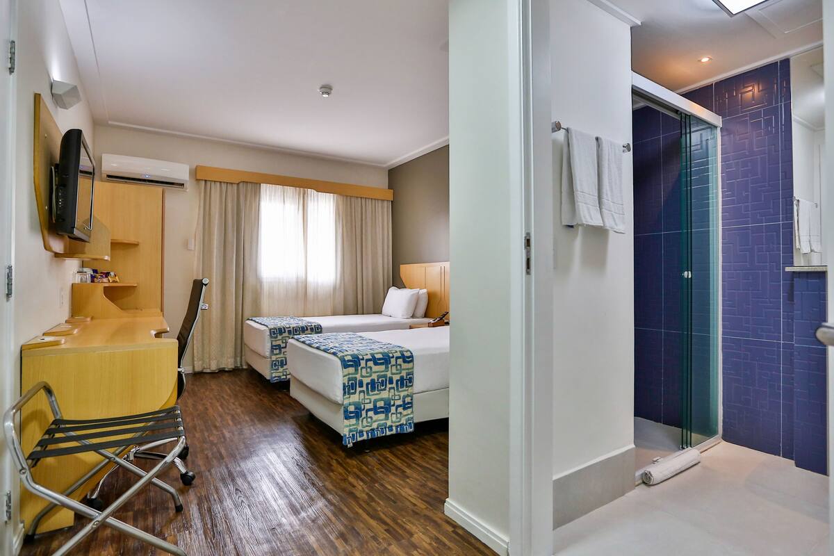 Une chambre d’hôtel équipée d’un lit, d’un bureau, d’une chaise et d’un espace douche.