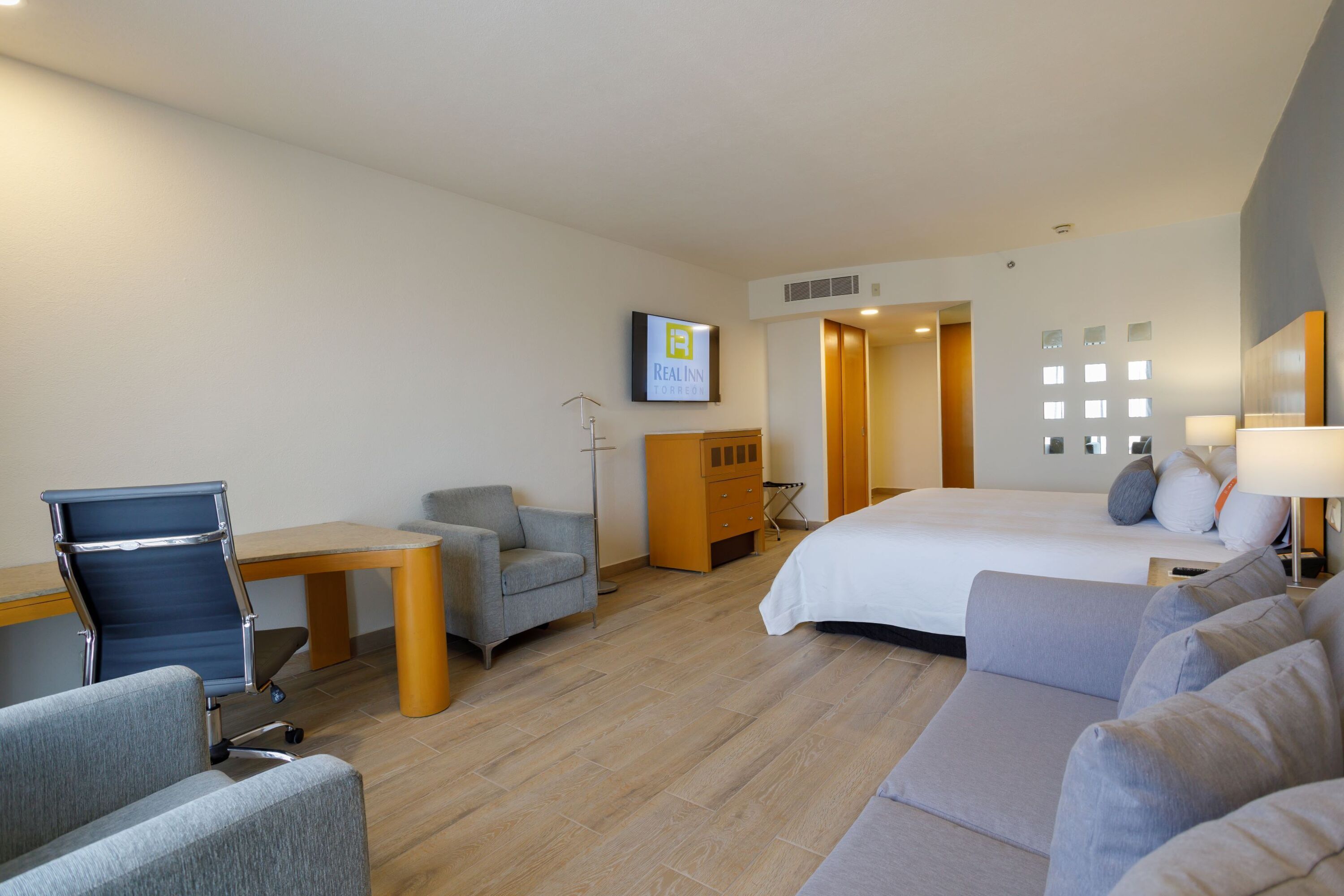 Une chambre d’hôtel équipée d’un lit, d’un bureau, d’une chaise, d’un canapé et d’une télévision.