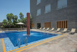 Una piscina al aire libre, sillones reclinables de piscina