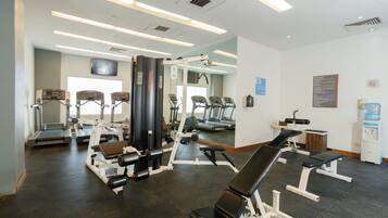 Un gimnasio con diferentes equipos de ejercicio, incluyendo cintas de correr, máquinas de pesas y una banca.