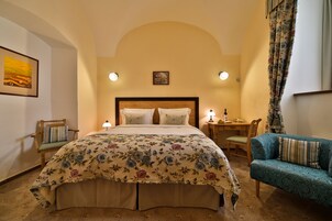 Quarto com uma cama grande, cabeceira de madeira, escrivaninha, cadeira e sofá.