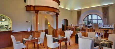 Un comedor espacioso con altos techos de madera, elegantes candelabros y vistas a través de ventanales abovedados.