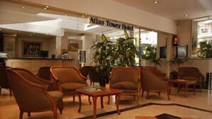 A lobby with a reception desk, several armchairs, a coffee table, and a large potted plant. - Atlas Tower Hotel (Buenos Aires)