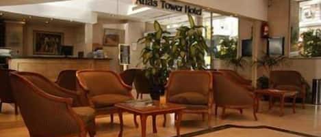 Un vestíbulo con mostrador de recepción, varios sillones, una mesa de centro y una planta grande en maceta.
