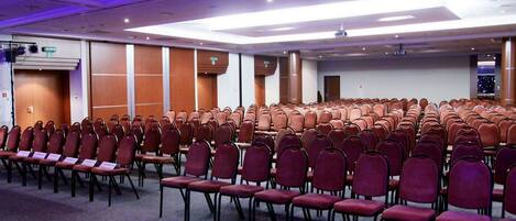 A conference room with rows of chairs and a stage area.