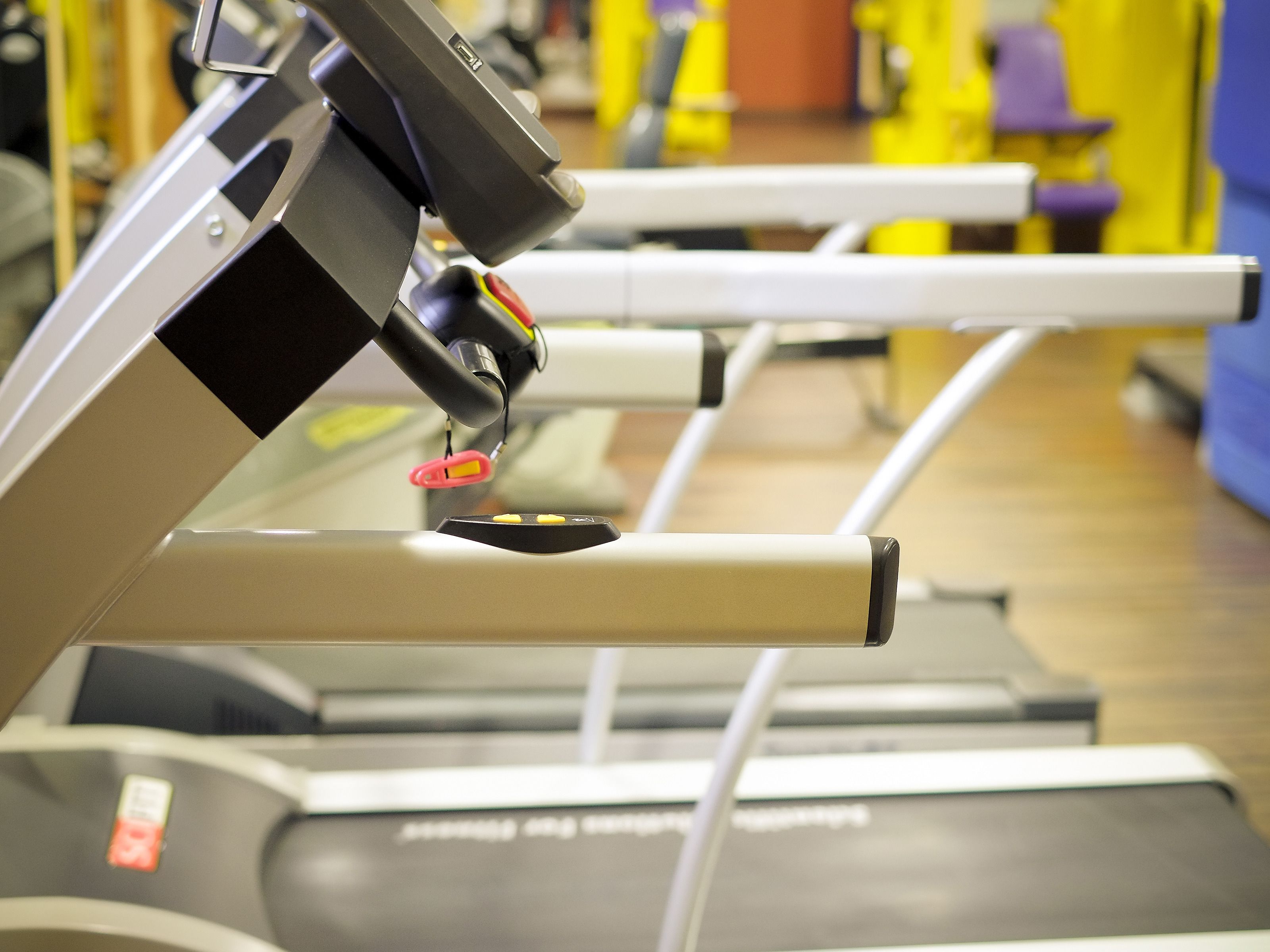 A treadmill in a gym with a control panel and a safety key.