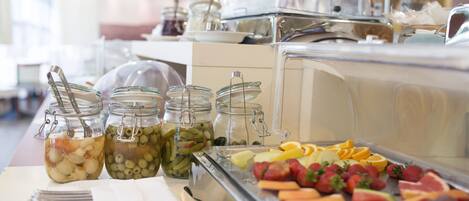 A buffet with various food items including fruits, vegetables, and pickled items.