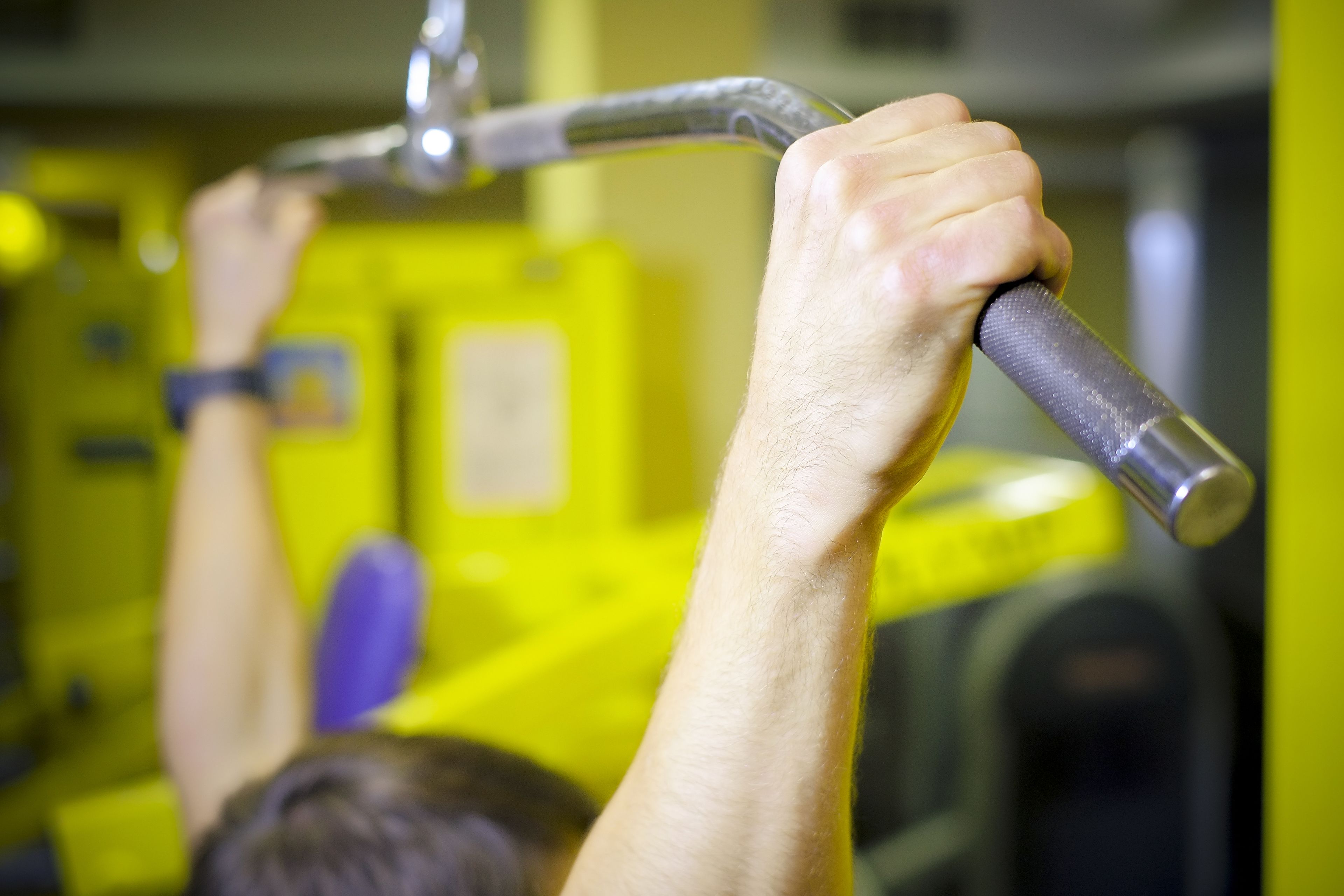 Primer plano de una mano agarrando el manillar de una máquina de ejercicios de gimnasio.
