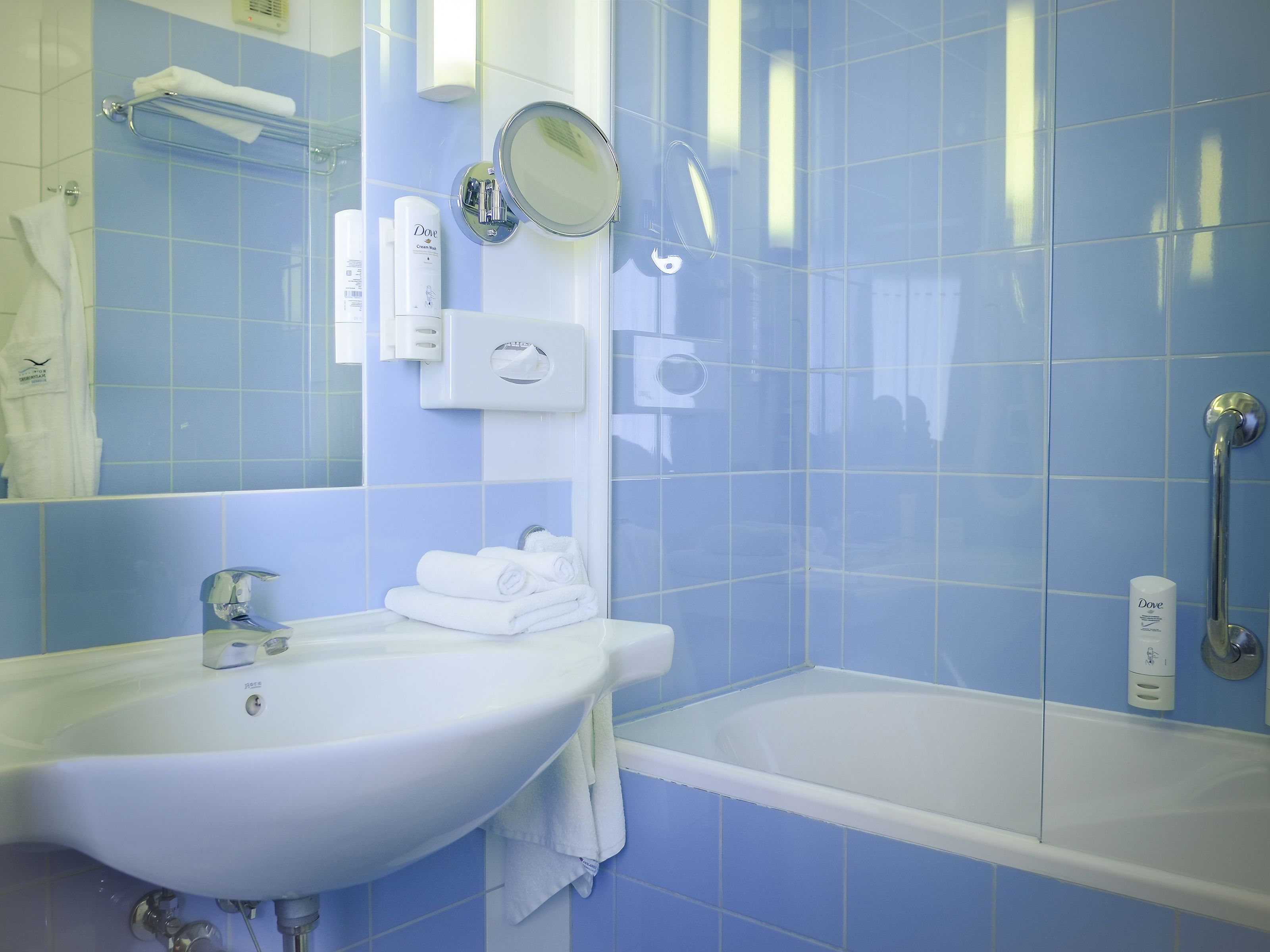 A bathroom with a sink, mirror, and bathtub.