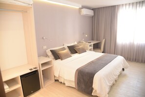 Una habitación de hotel moderna con una cama bien hecha, un escritorio y una silla.