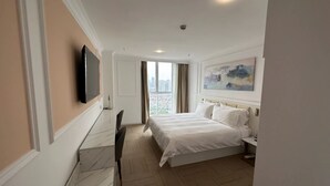Una habitación de hotel con cama, escritorio, silla, televisor y un cuadro en la pared.