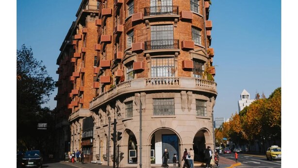 Un edificio de varios pisos con fachada curva, amplias ventanas y una entrada central con marquesina.