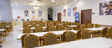 Ein geräumiger Bankettsaal mit Marmortischen und aufwendigen Stühlen, der Kunstwerke an den Wänden und ein modernes Decken-Design zeigt.