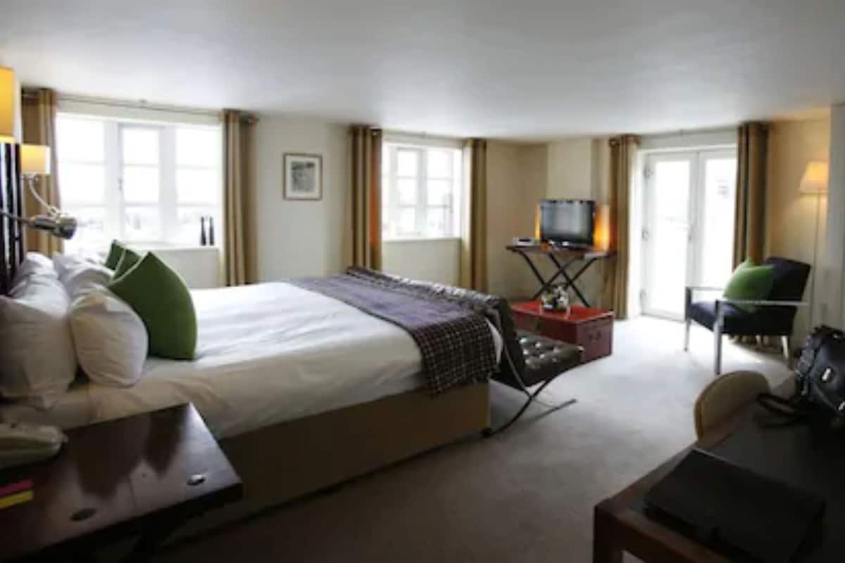 Ein Hotelzimmer mit einem großen Bett, einem Schreibtisch, einem Stuhl, einem Fernseher und einem Kleiderschrank.