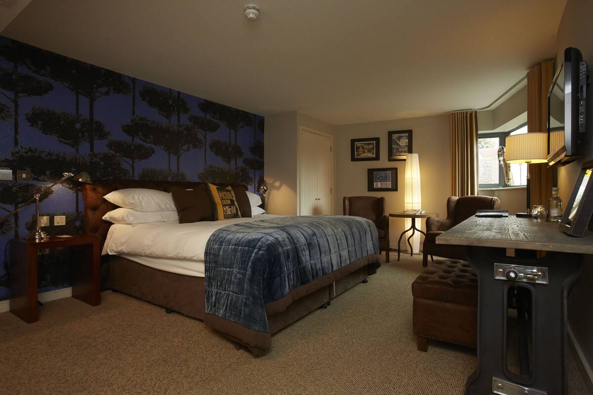 Ein Hotelzimmer mit einem Bett, einem Schreibtisch, einem Stuhl, einem Fernseher und einer Lampe.