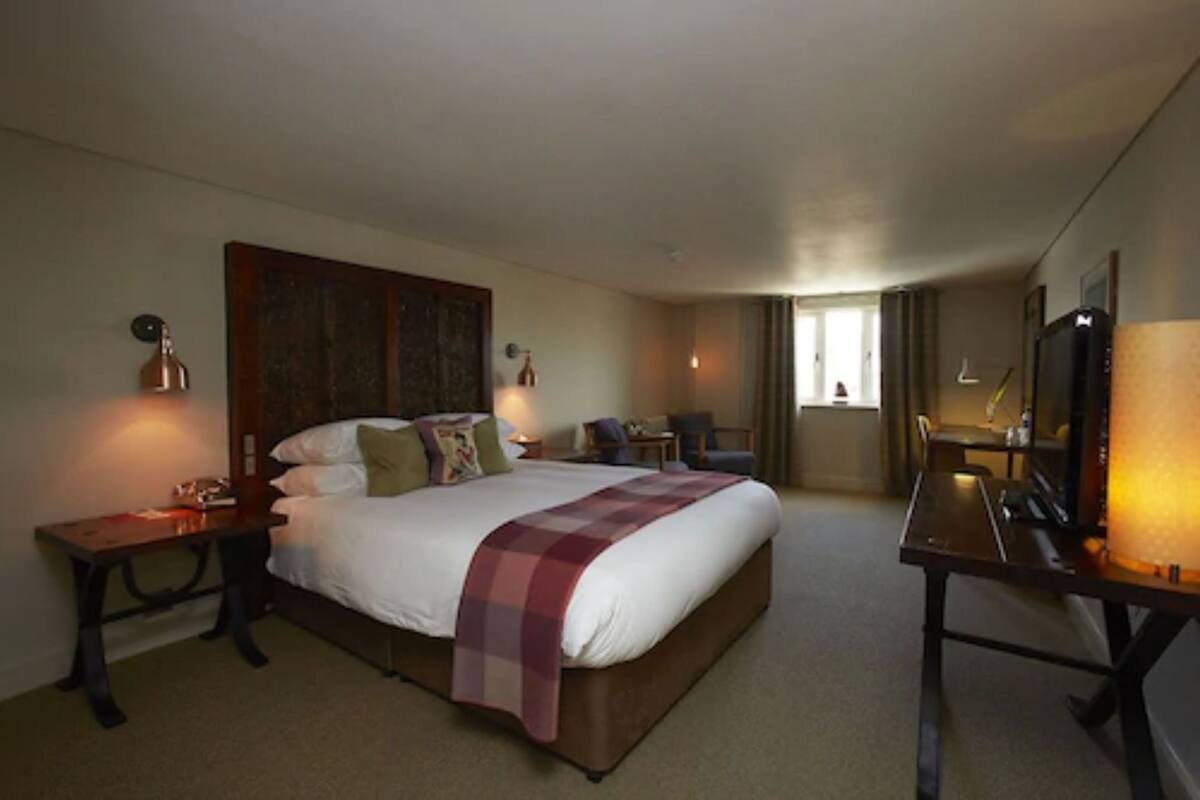 Ein Hotelzimmer mit einem großen Bett, Nachttischen, einem Schreibtisch und einem Sessel.