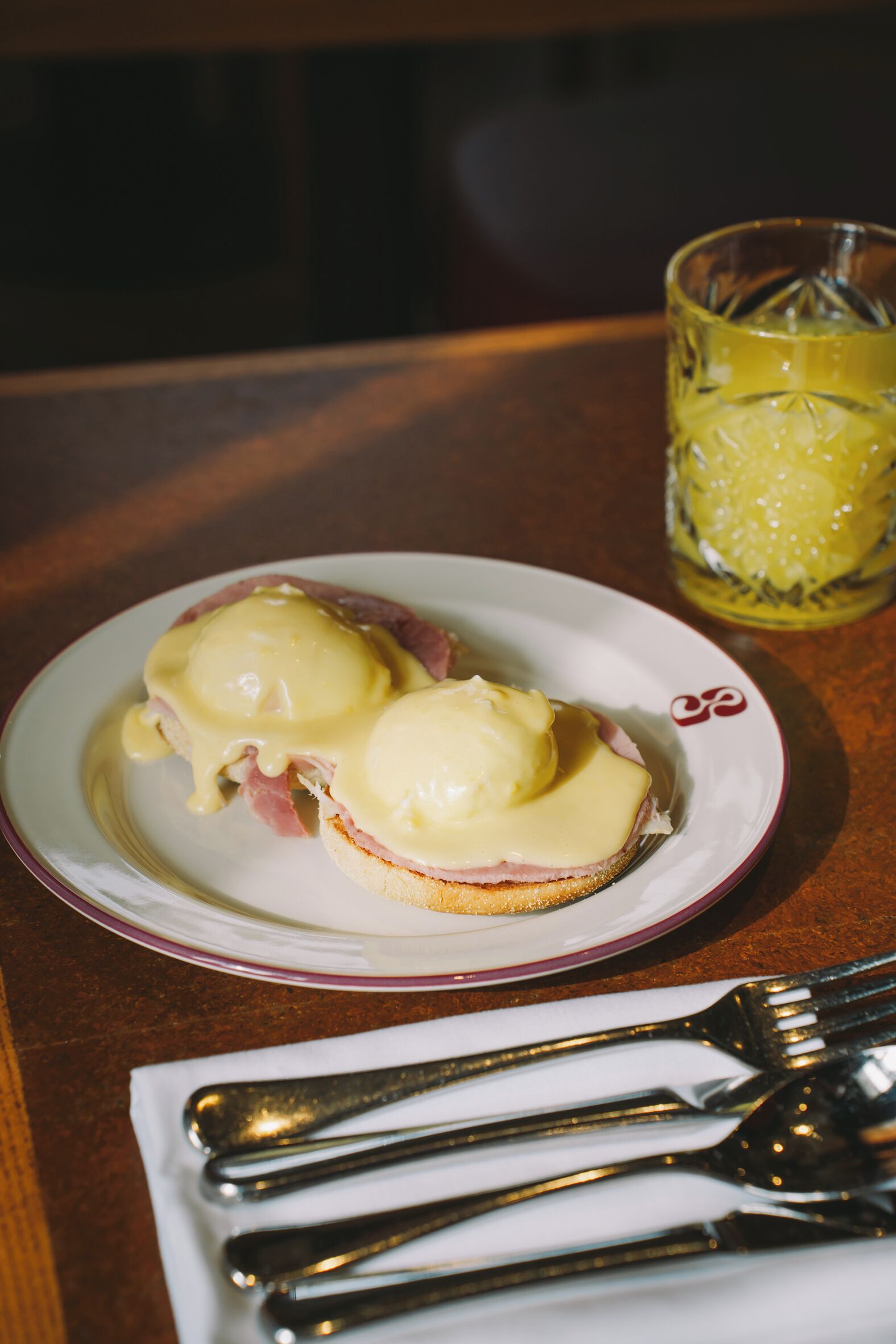 A plate with a sandwich and a glass of beverage on a table.
