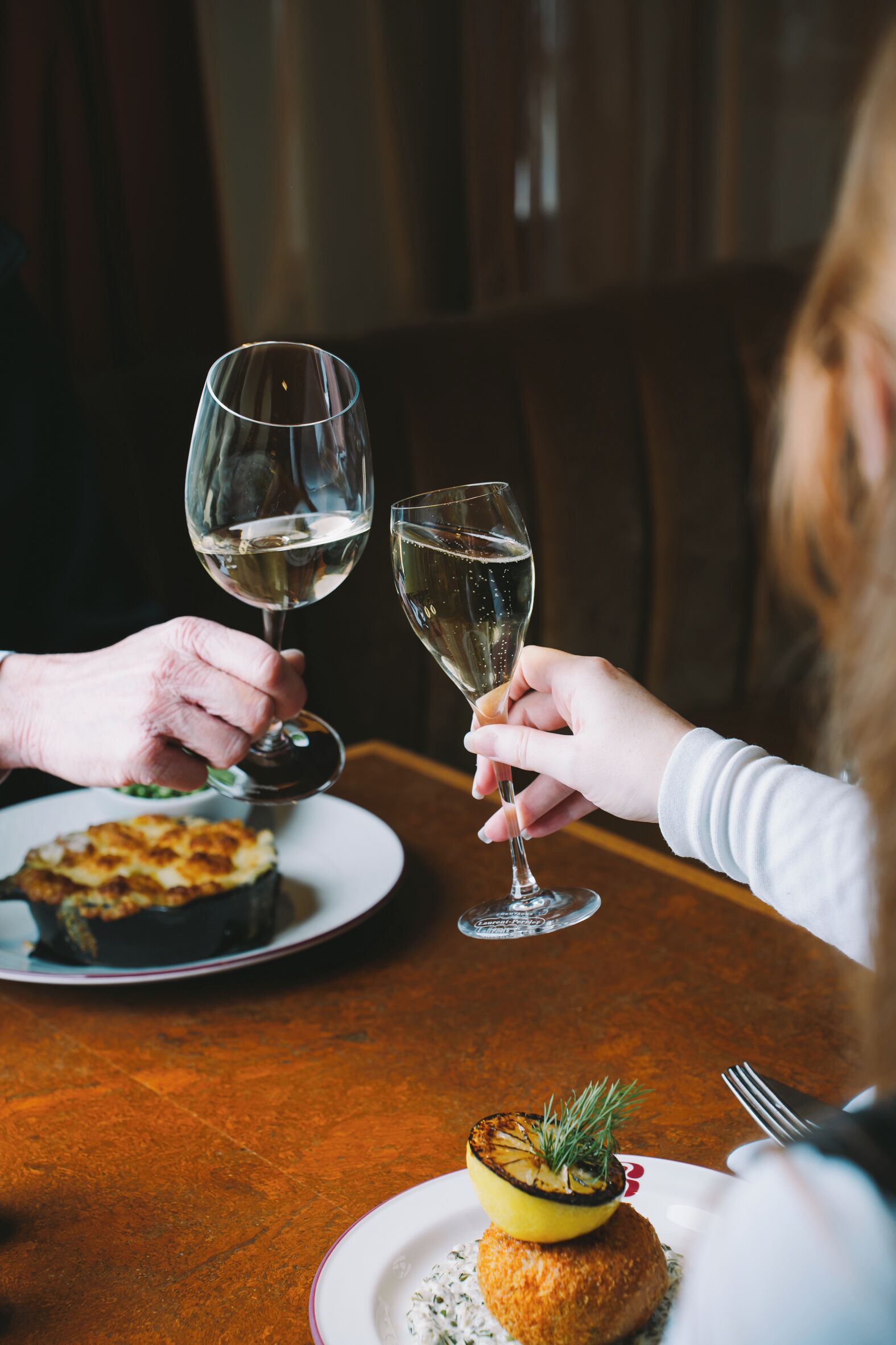 A dining table with a plate of food and two wine glasses.
