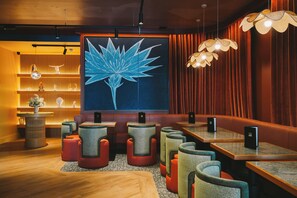A restaurant interior with wooden tables, cushioned seating, a large wall-mounted artwork, and pendant lighting. - Salthouse Harbour Hotel and Spa (Ipswich)