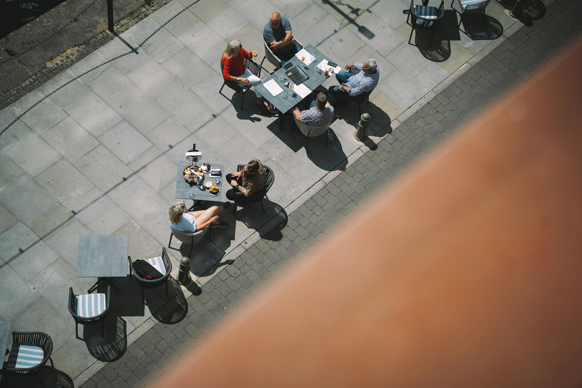 An outdoor café with tables and chairs arranged on a paved area.
