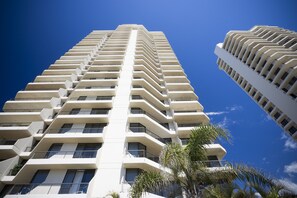 Un edificio alto con varios balcones y un cielo azul despejado.