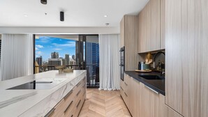 A modern kitchen with a marble countertop, wooden cabinetry, and a view of the cityscape. - Paradise Centre Apartments (Surfers Paradise)