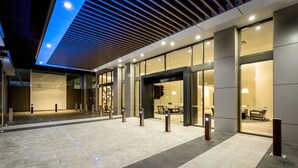 A modern hotel lobby with a spacious entrance, glass doors, and a seating area visible through the windows. - Paradise Centre Apartments (Surfers Paradise)