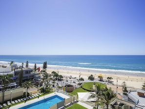 Ein Hotel mit Swimmingpool, Blick auf den Strand und Palmen.