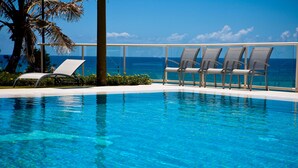 A clear blue pool with lounge chairs and a view of the ocean. - Paradise Centre Apartments (Surfers Paradise)