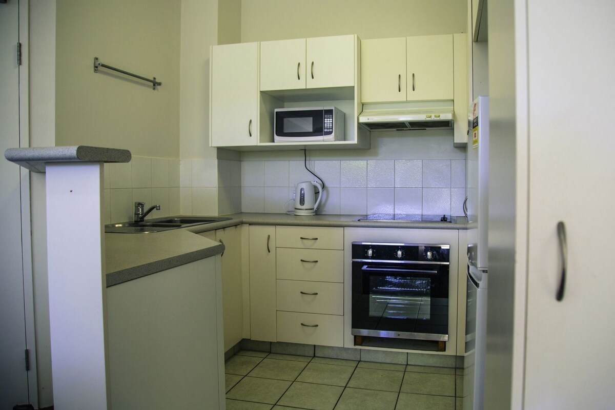 A compact kitchen with a microwave, kettle, and oven.