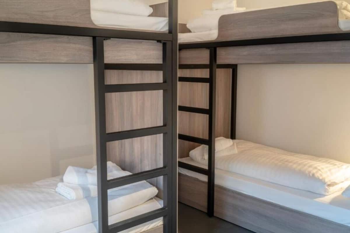 A bunk bed room with wooden frames and white bedding.