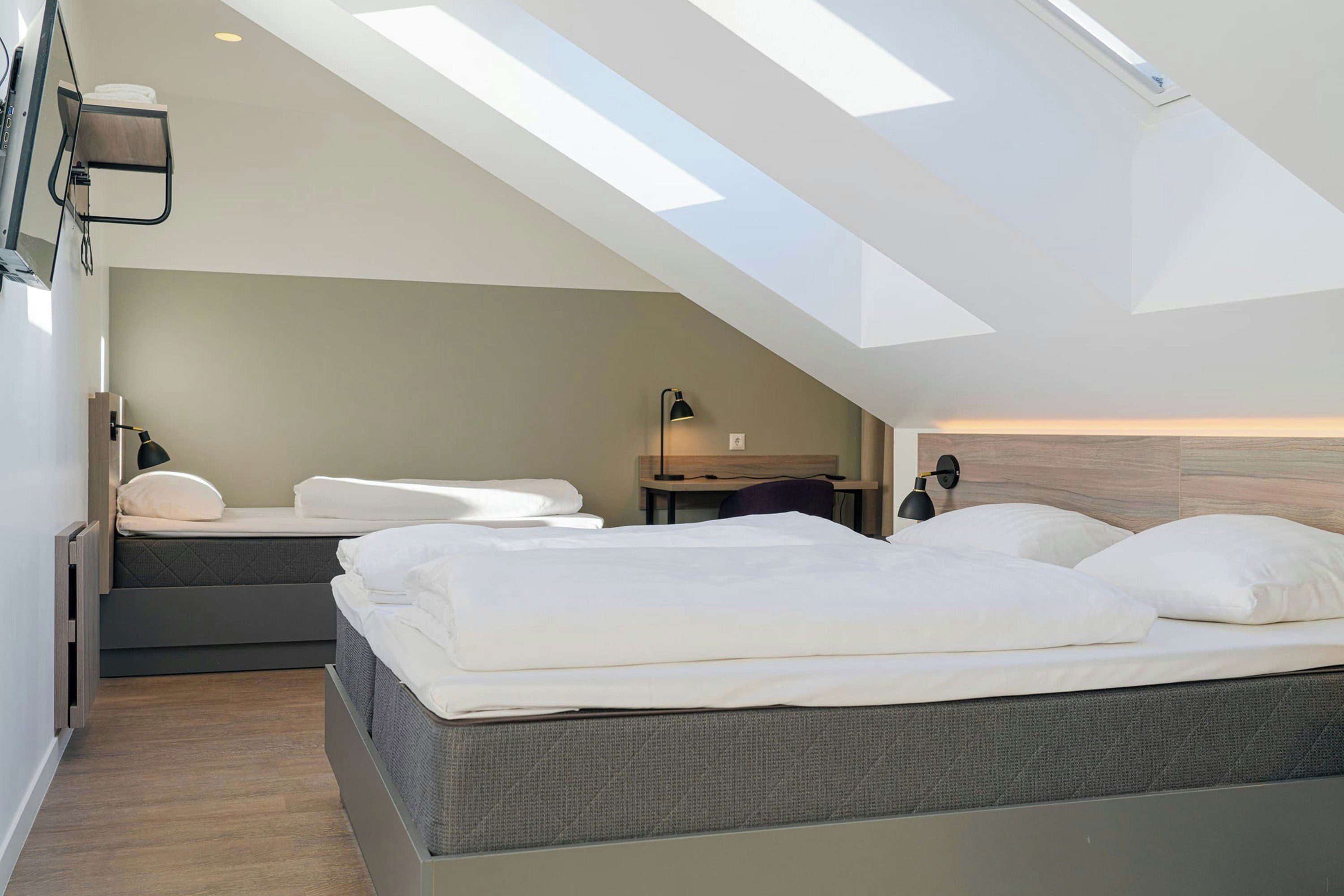 Un dormitorio moderno con tragaluces, cama, escritorio y silla.