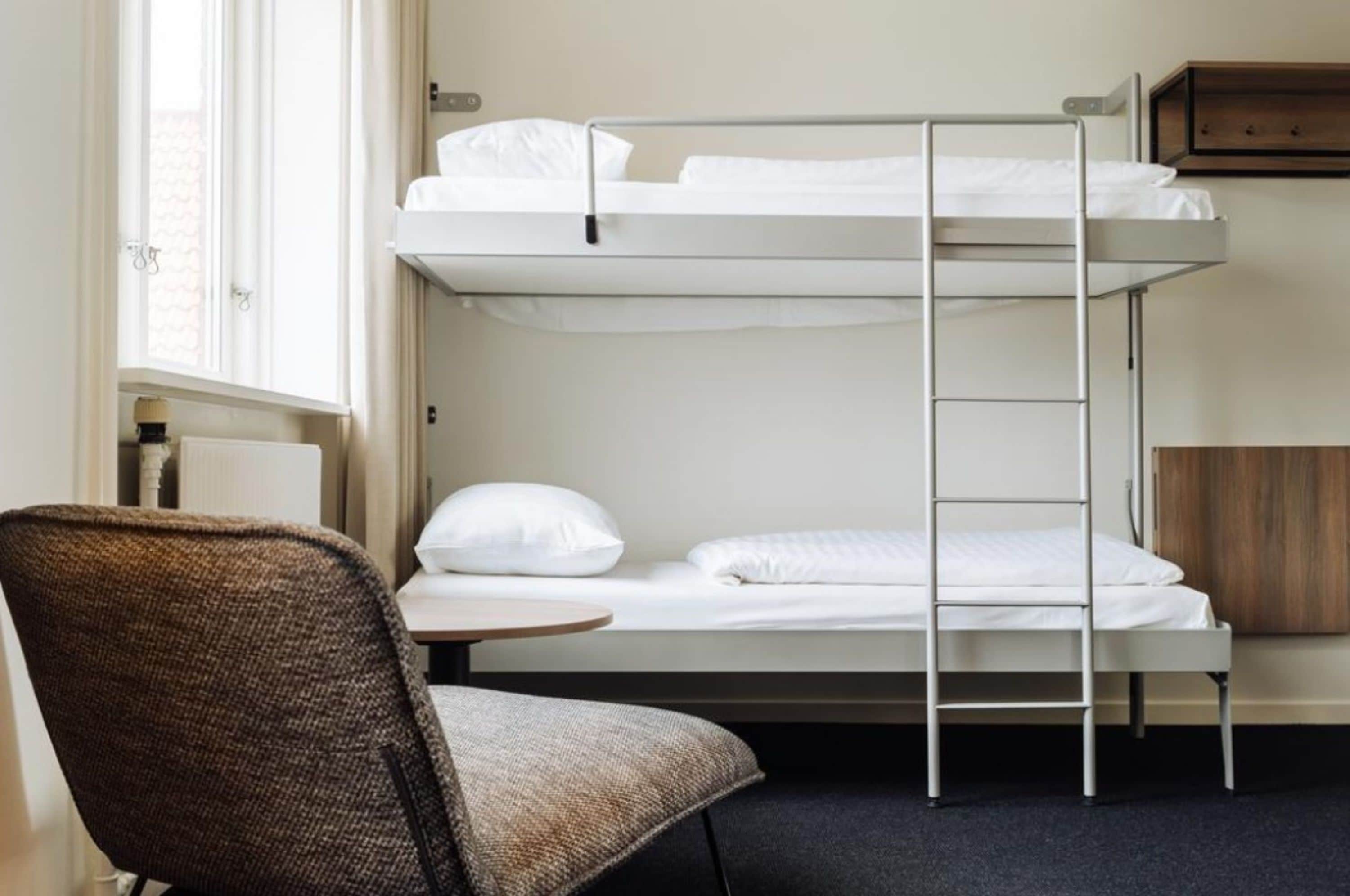 A bunk bed room with a chair and a small table.