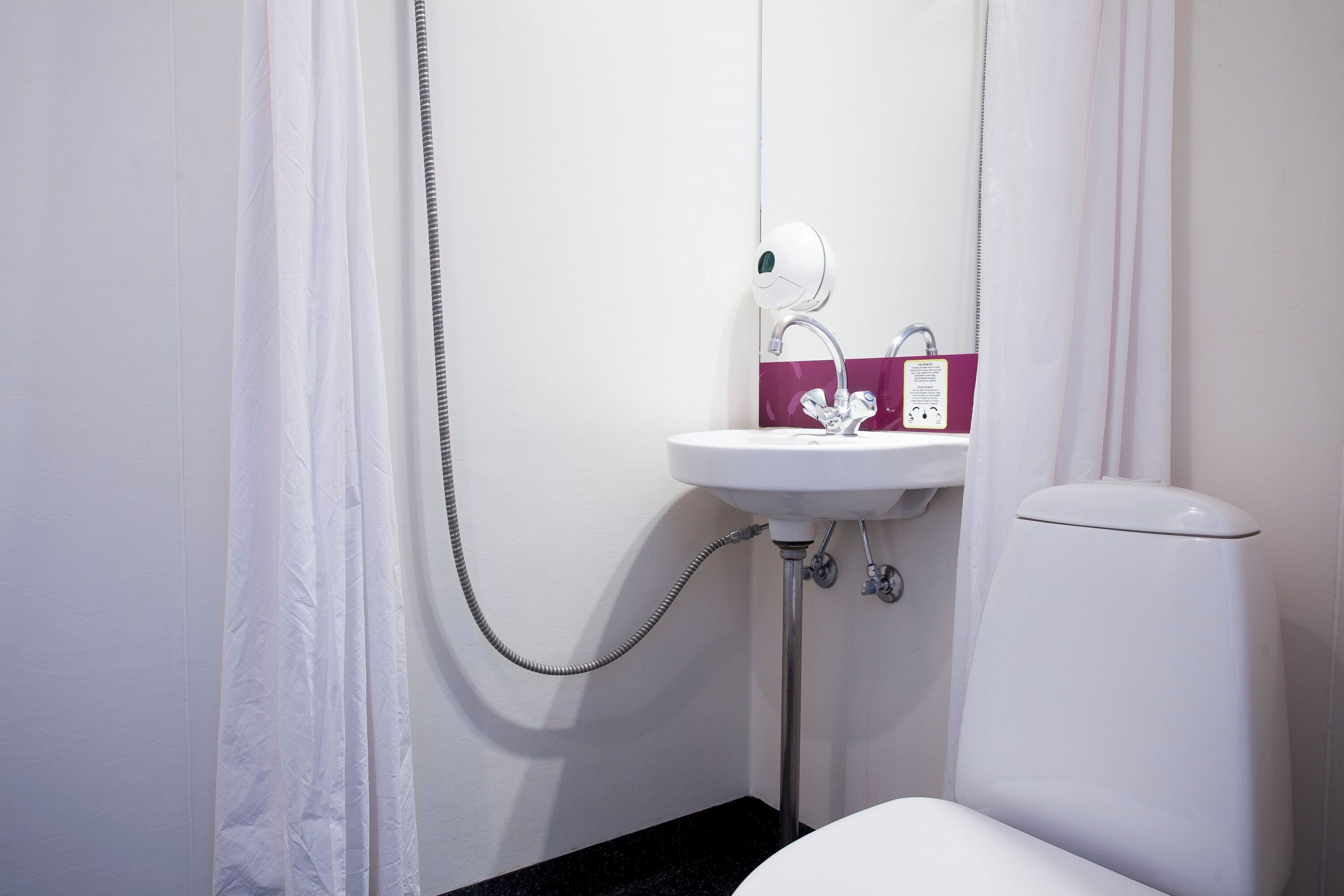 Ein Badezimmer mit weißem Waschbecken, Toilette und Duschvorhang.