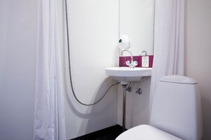 Un baño con lavamanos blanco, inodoro y cortina de ducha.