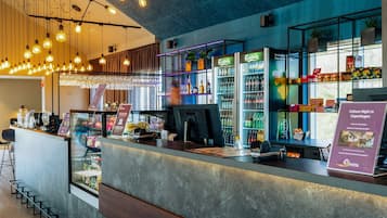 Un espace bar moderne comprenant un comptoir, des tabourets de bar et une variété de boissons et d’en-cas.