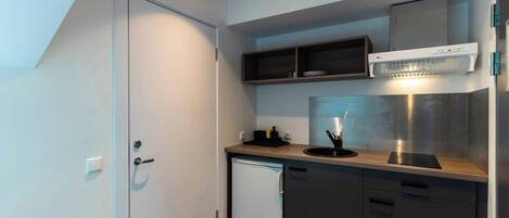 Una cucina compatta con lavastoviglie integrata, forno a microonde e cappa aspirante in acciaio inossidabile.