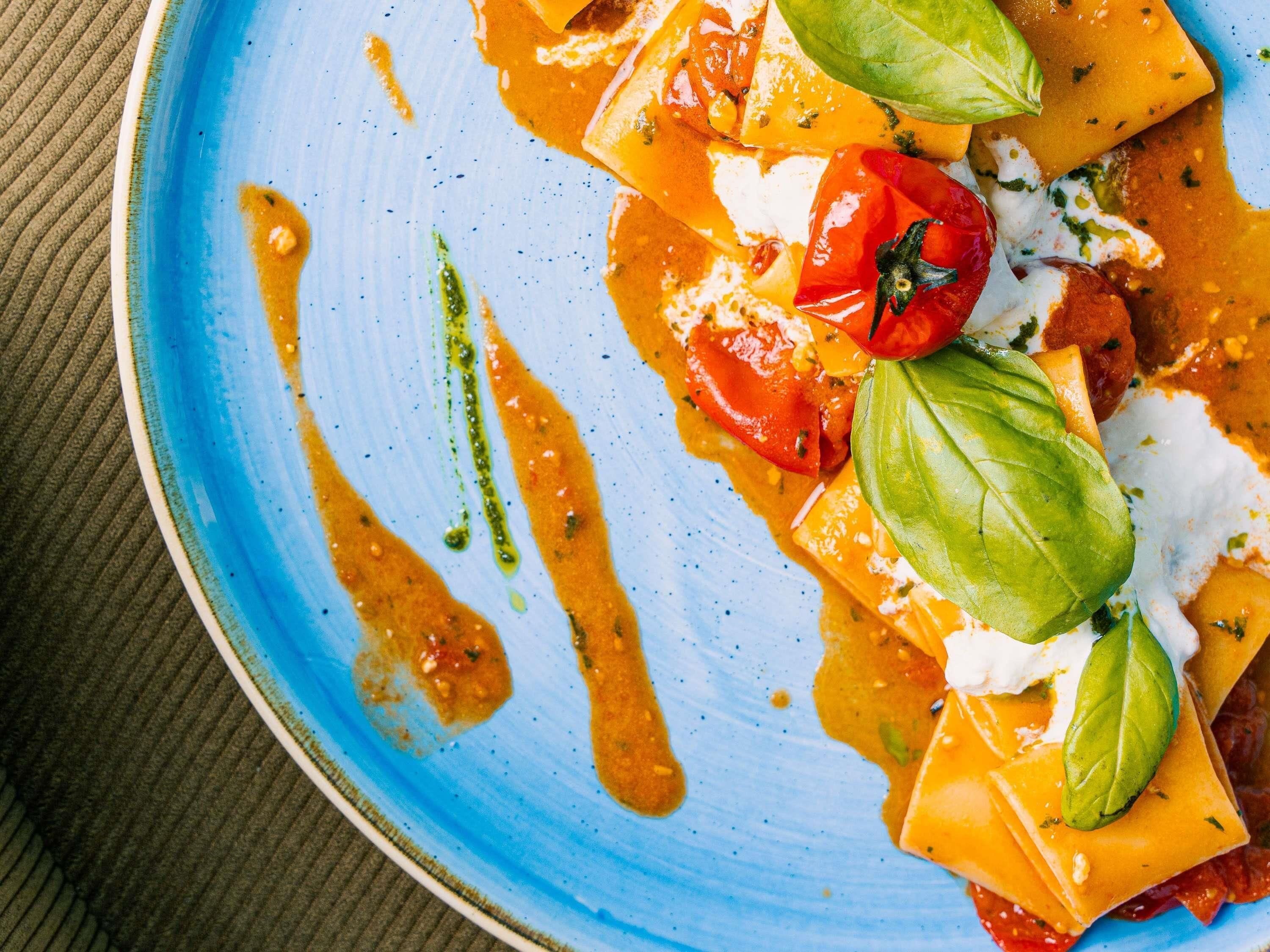 A plate of food with tomatoes, basil, and a creamy sauce.