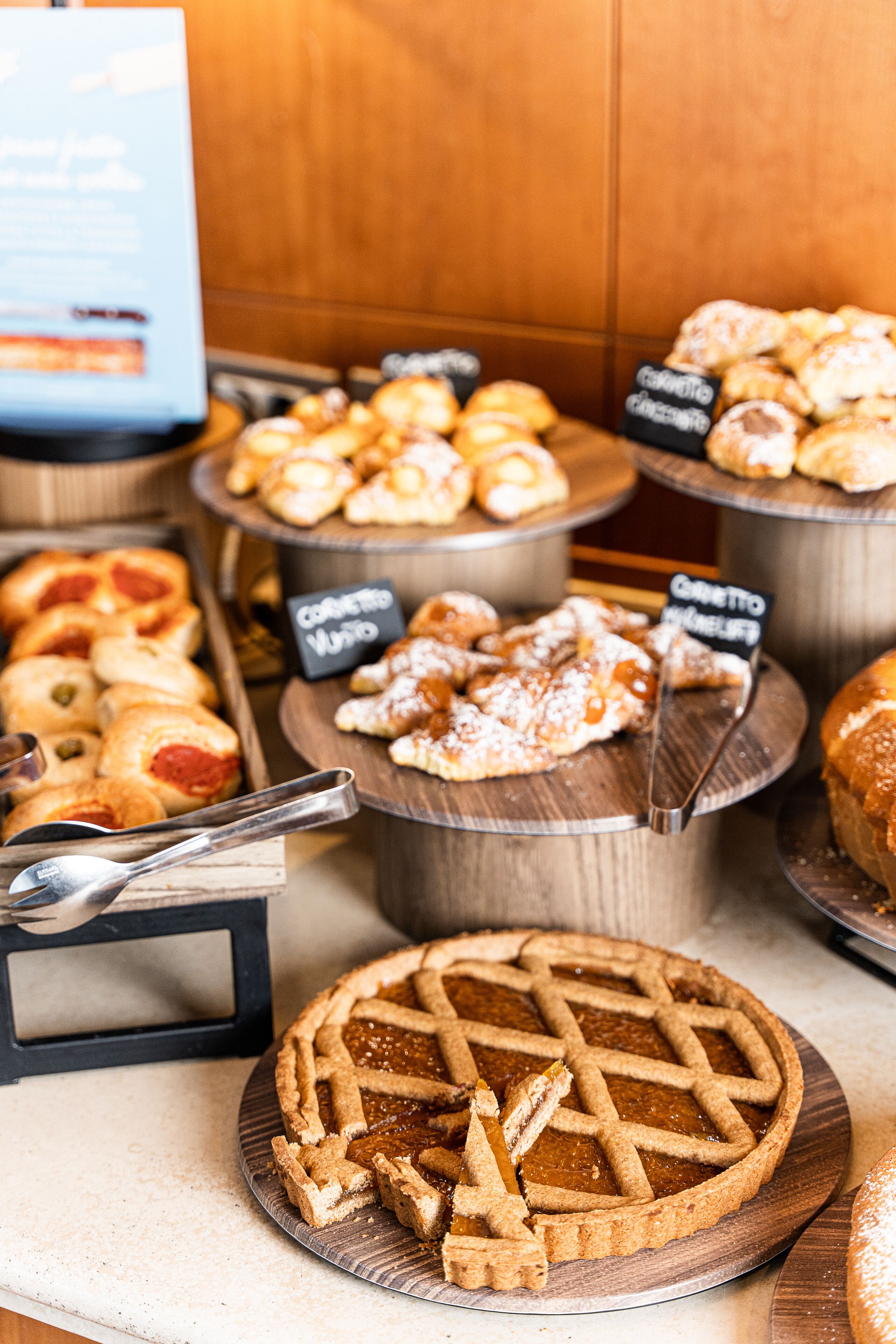 A variety of baked goods displayed on wooden stands, including pies and pastries.