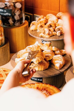 A variety of pastries on wooden stands, including croissants and a sign indicating a chocolate selection.
