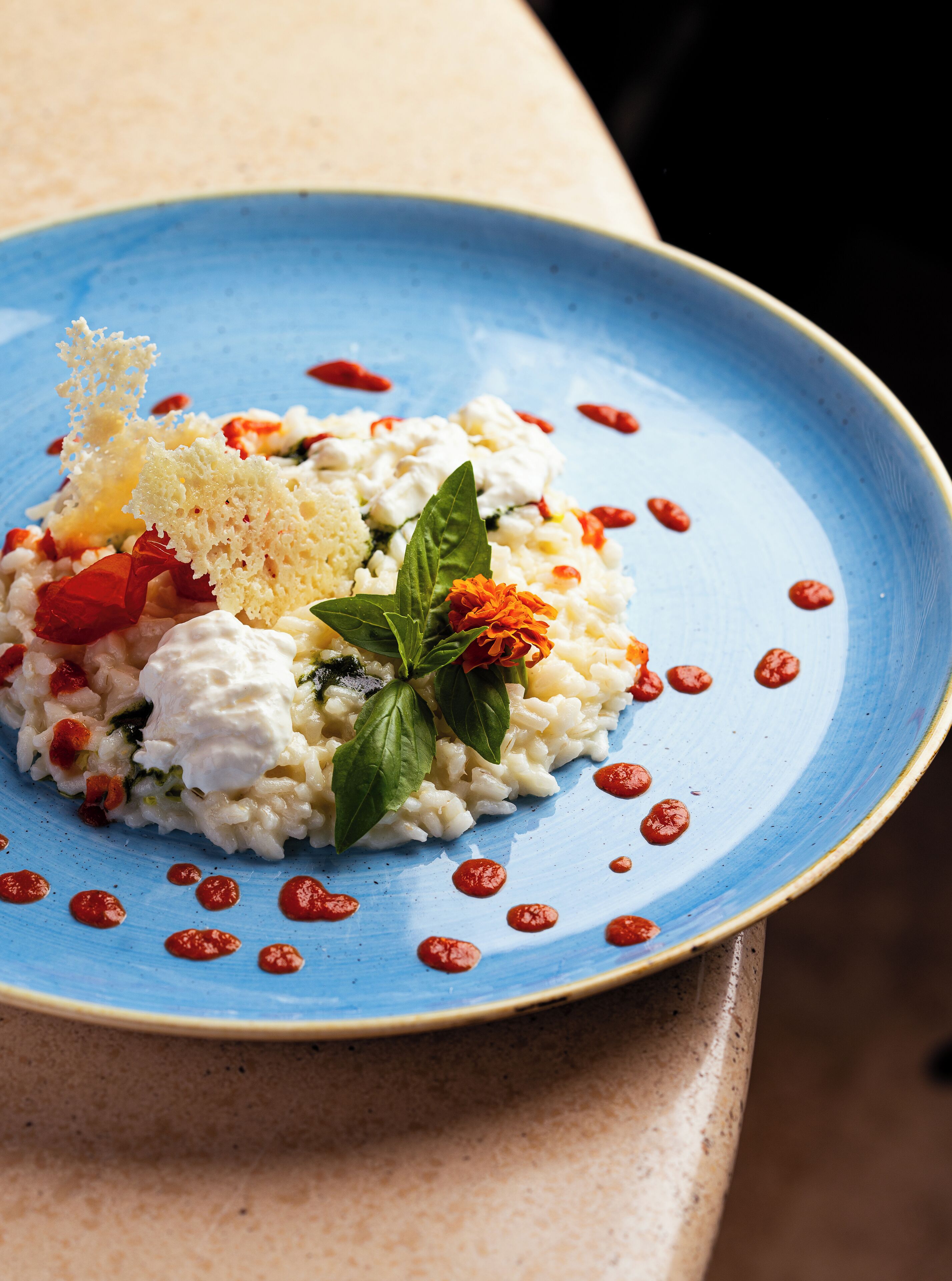 A plate of food with a blue rim, garnished with basil and red chili flakes.