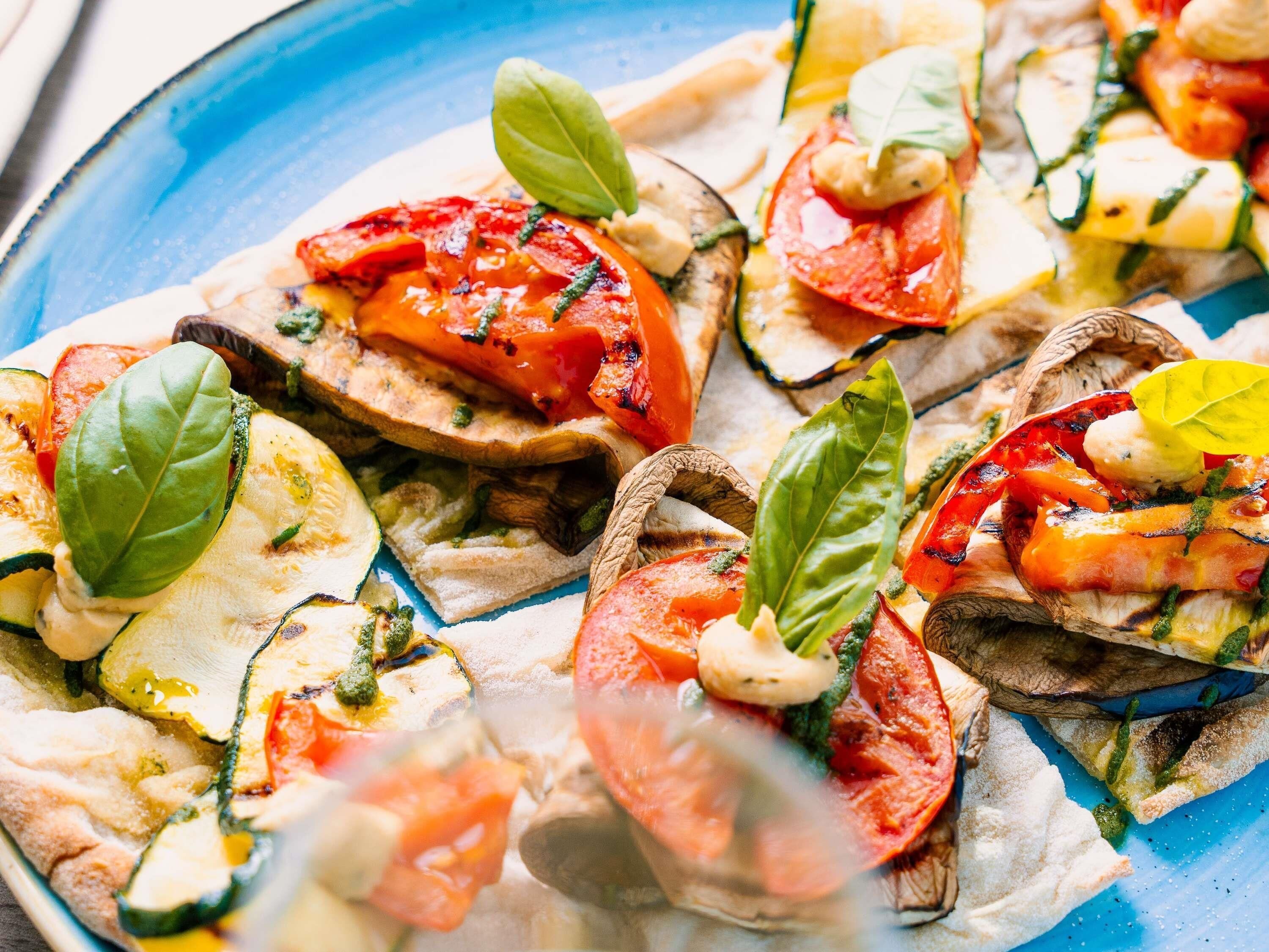 A close-up of a dish with grilled vegetables and cheese on a blue plate.