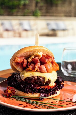 A burger with bacon, cheese, and lettuce on a plate.