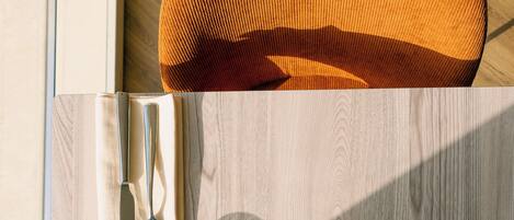 Una mesa de comedor con superficie de madera, un cuenco de vidrio, una servilleta blanca, un tenedor, un cuchillo y un candelabro.