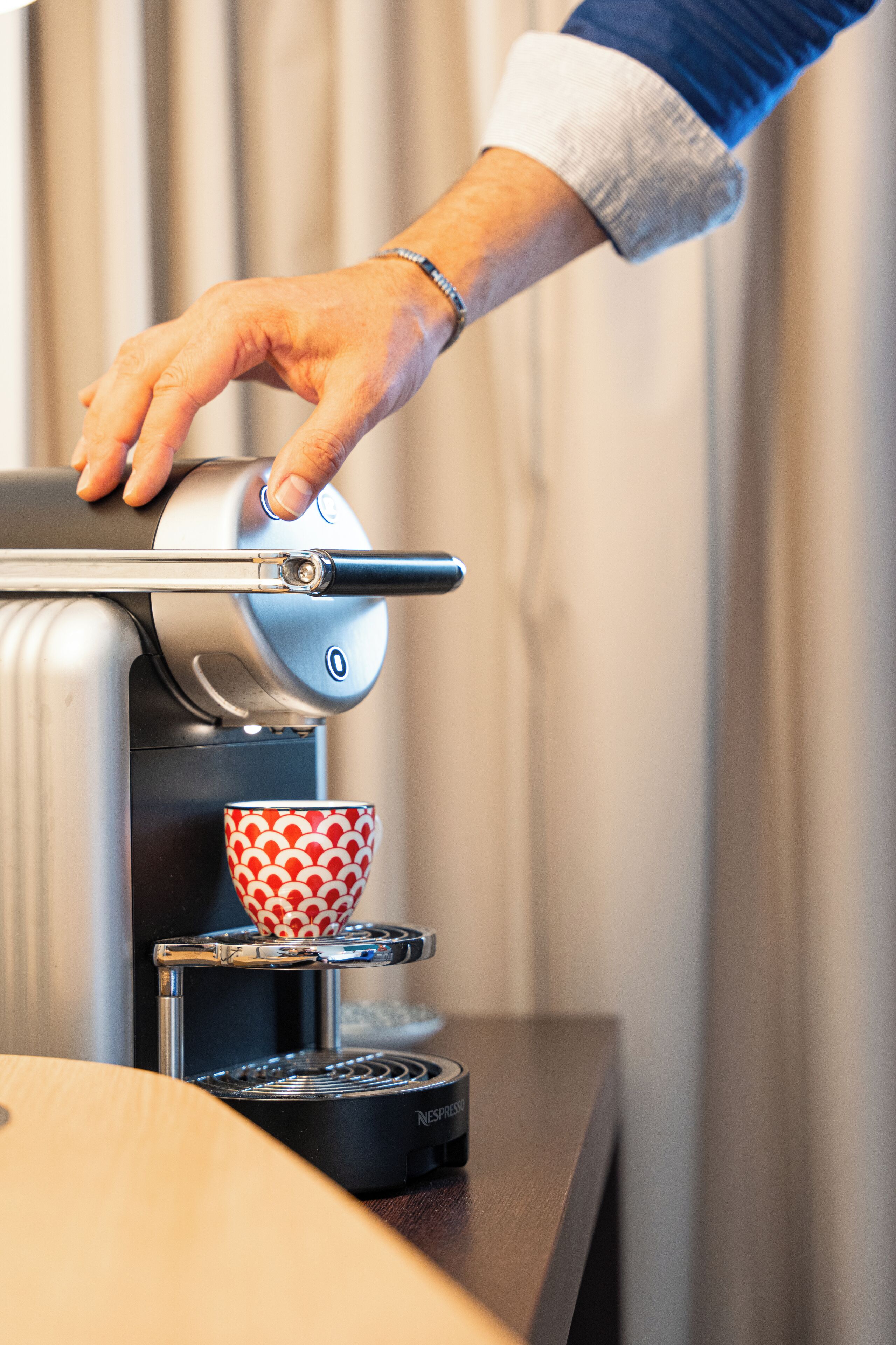 Una mano colocando una taza debajo de una máquina de café.