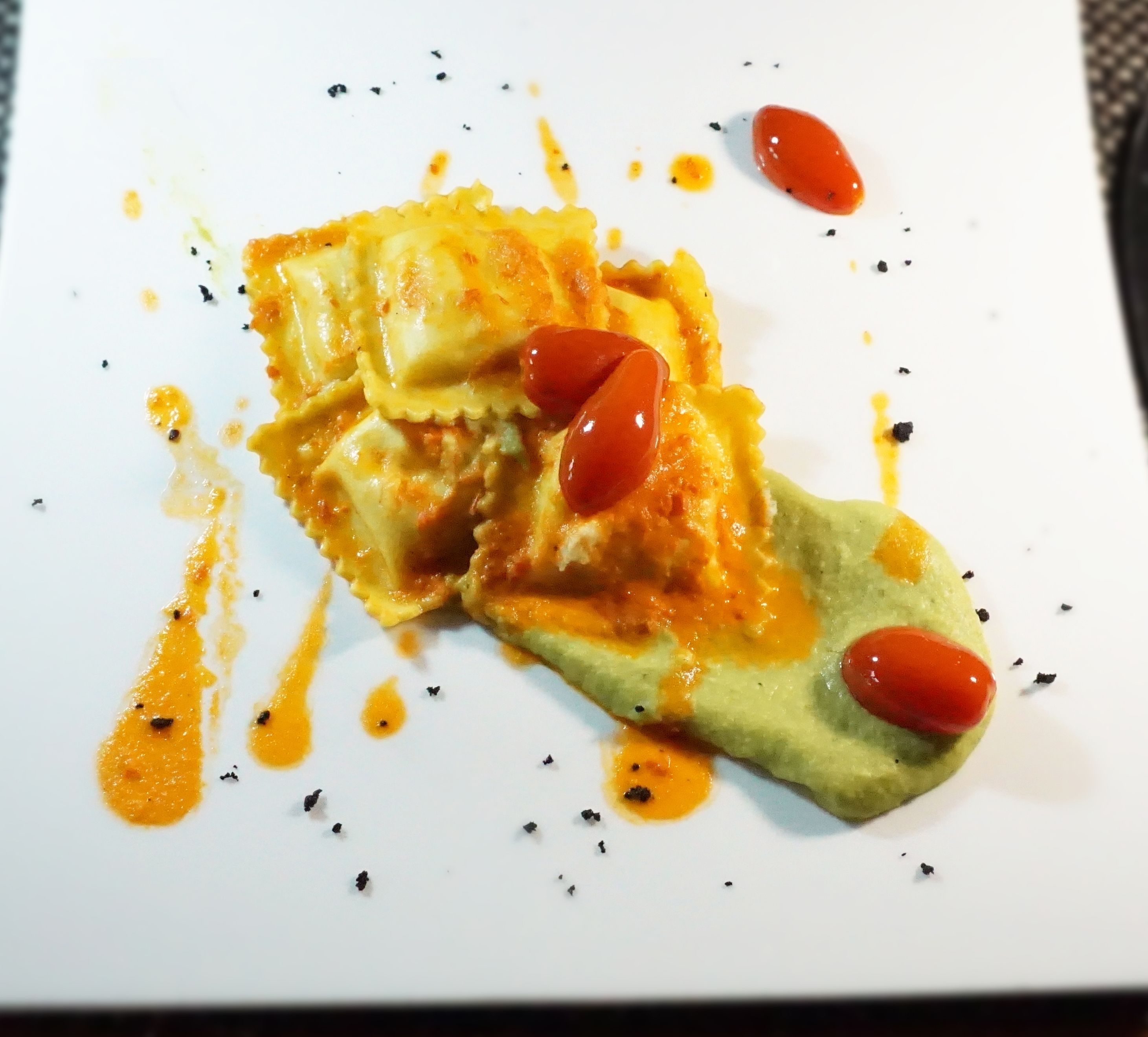 Un piatto di ravioli e pomodorini ciliegino su un piatto bianco.