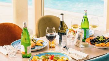 A dining table with plates of food, wine glasses, and bottles, overlooking a pool area.