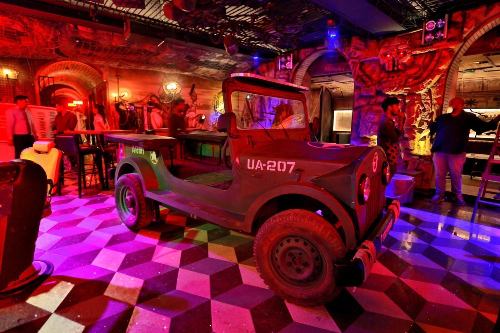A vintage military jeep labeled UA-207 in a dimly lit room with checkered flooring and a mural in the background.