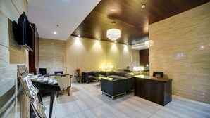 Um lobby moderno com balcão de recepção, área de estar e um lustre.